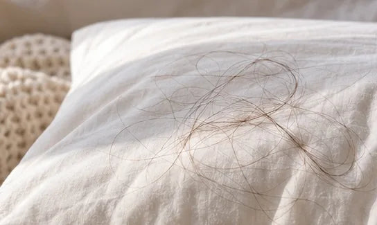 Pelos sueltos sobre una almohada blanca