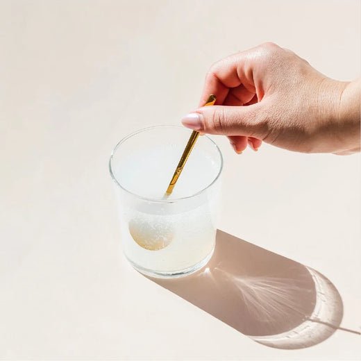 Una mano revolviendo el vaso mientras el polvo burbujea